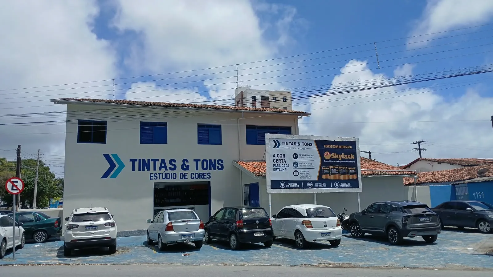 Fachada da loja Tintas & Tons Estúdio de Cores na Av. Camilo de Holanda, com placa de revendedor autorizado Skylack e estacionamento em frente